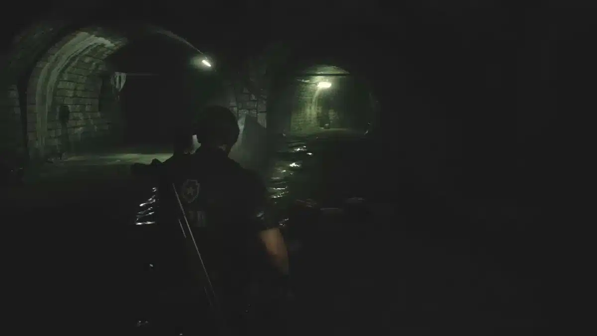 Leon S Kennedy in a dark uniform stands in a dimly lit sewer tunnel with a firearm, surrounded by wet, arched brick walls.
