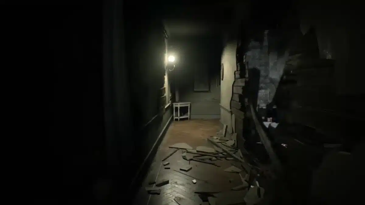 Dimly lit hallway in the Resident Evil 7 Basement with broken wall and debris on the floor.
