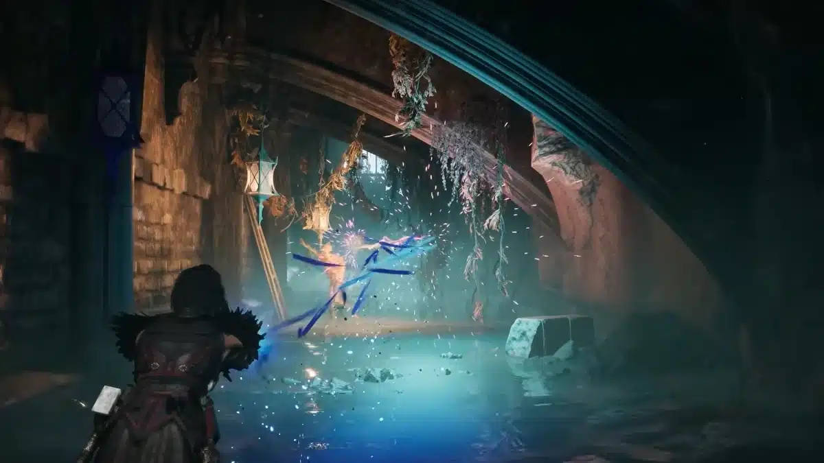 A figure in dark, ornate armor fires a stream of blue energy at a swirling mass of light and ribbons in a dark, cavernous environment with hanging plants and dripping water.