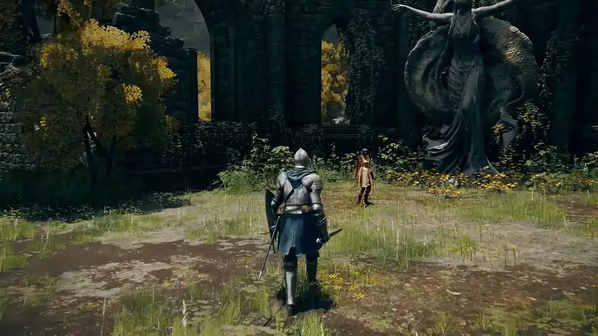 A knight in silver armor faces away from the camera, walking towards a second, smaller figure standing near a large, dark statue of a draped woman. The scene takes place in an overgrown ruin with yellow trees and mossy stone structures.