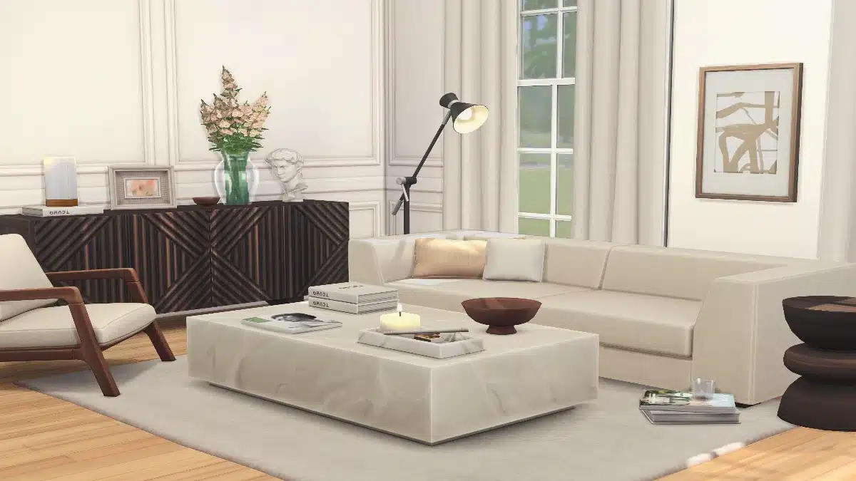 A modern living room with a sectional sofa, a marble coffee table with a candle and books, and a dark wood cabinet.