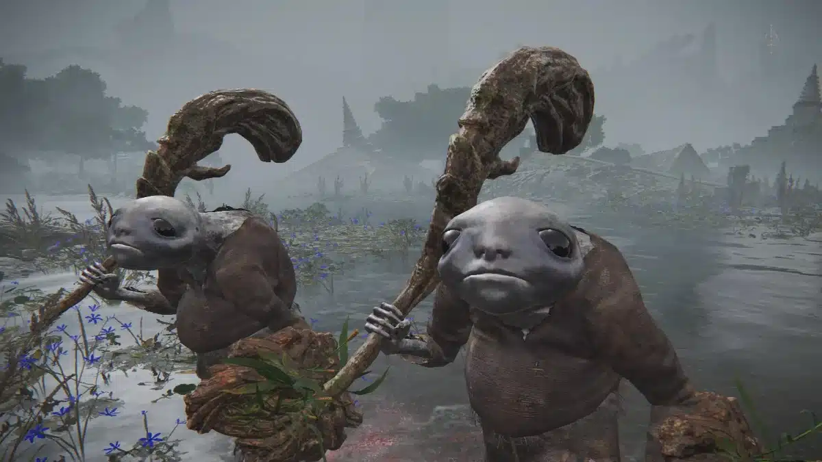 Two grey-skinned, amphibian-like creatures in dark robes stand in shallow, misty water, each holding a gnarled wooden staff.