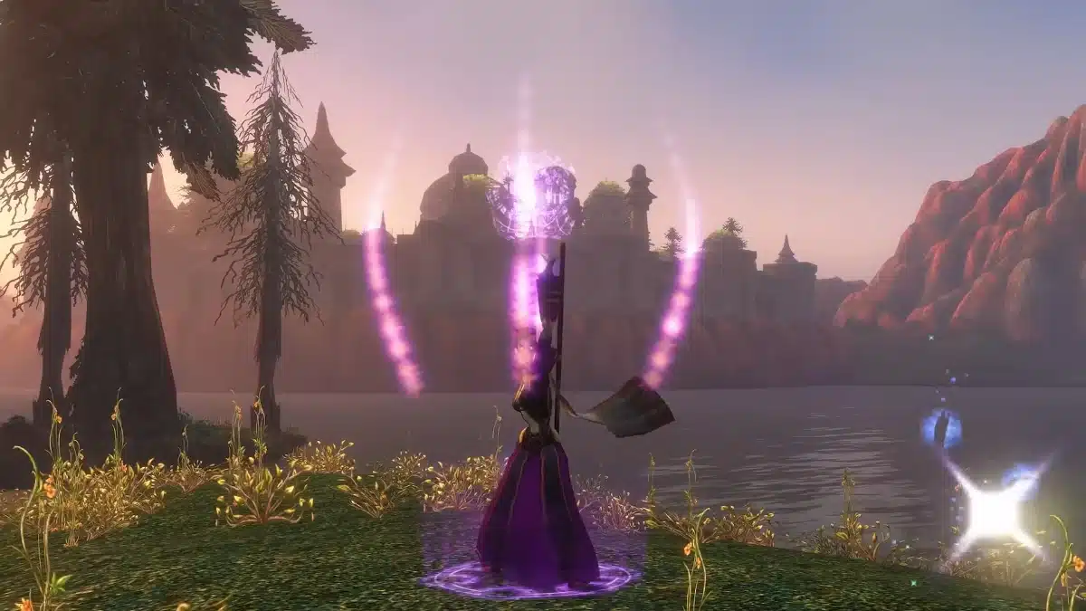 A figure in a dark purple gown stands on a grassy knoll, casting a spell that emits purple light and a shimmering orb above their head. In the background, a tranquil lake reflects the soft, hazy light of sunset, with distant buildings and a rugged mountain range silhouetted against the pastel sky.