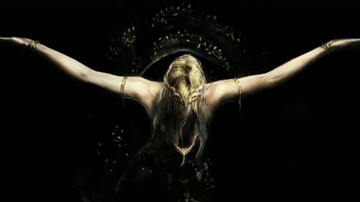 A blonde figure with arms outstretched and a crown of leaves on their head against a dark background.